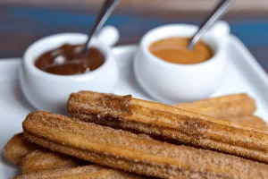 Close-up image of churros filled with dulce de leche and chocolate, showcasing the rich, creamy fillings inside crispy churro shells.